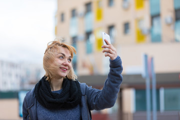 blonde young girl in the city happy with the mobile