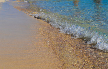 a small wave runs to the sandy beach
