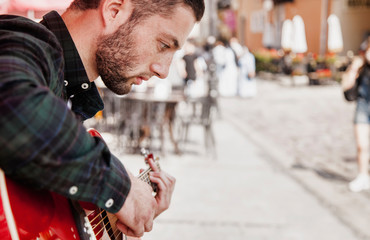 Handsome caucasian man playing the guitar outdoors. Music, art, creativity concept.