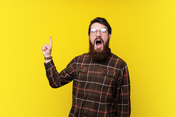 Surprised handsome bearded guy, pointing up  at copy space with  opened mouth expression