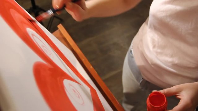 closeup artist painting a big red heart on a canvas