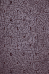 Leather background texture. Purple imitation leather book cover with embossed letters and numbers. High resolution image or macro.