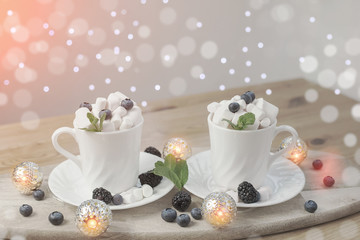 coffee with milk and marshmallows with blueberries and blackberries in white cups on wooden textured background. image