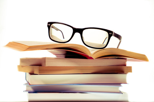 B&uuml;cherstapel zum Studieren mit einer schwarzen Brille darauf