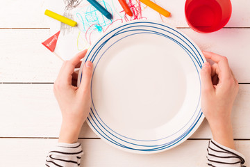 Table setting for kids - empty plate in child's hands © pinkyone