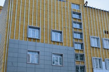 Insulation for thermal protection to the shell of the house. Construction site, insulation of the office facade of the building. Insulation on a brick wall with mineral wool and glue