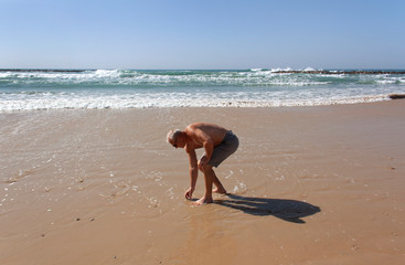 Resting man picks up a pebble from the sand