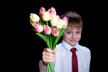 Small boy in a shirt with tie holding a bouquet of tulips. Isolate on black background.