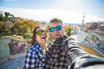 Travel couple happy making selfie portrait with smartphone in Park Guell, Barcelona, Spain.