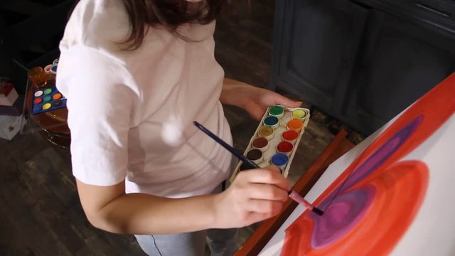 woman artist painting on the easel in her studio
