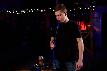 Man makes hookah. Modern hookah with coconut charcoal for relax and shisha smoke.