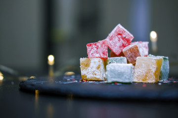 close up traditional Turkish delights - lukum isolated on dark background with light bokeh