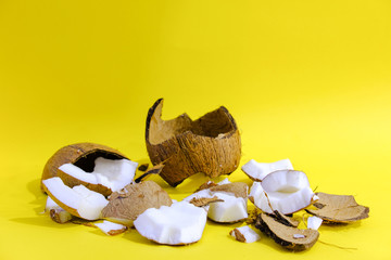 close up raw fresh coconut pieces isolated on a bright yellow background/ creative concept of tropical fruit