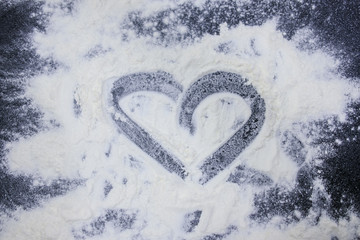 close up sprinkled flour in heart shape/ preparing for cooking 