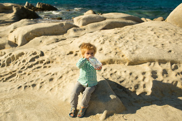 Child drinks water in the desert. Thirst. Clear water in a plastic bottle. Drink for children. Boy with soda sparkling water by the sea.