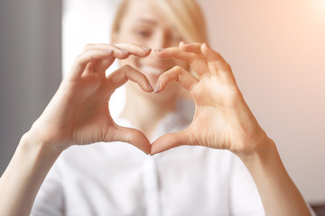 Blurred woman showing hand heart gesture