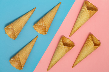 Ice cream waffle cones on pastel pink and blue background. Waffle ice cream cone. Top view. Flat lay. Modern minimal composition