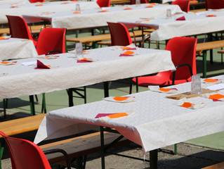 tables set outdoors for a community lunch with lots of guests