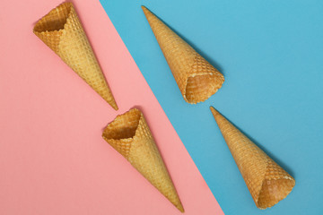 Ice cream waffle cones on pastel pink and blue background. Waffle ice cream cone. Top view. Flat lay. Modern minimal composition