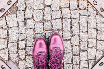 Feet selfie. Fashionable burgundy boots on the city pavement. Rainy weather