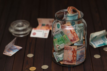 Russian banknotes in glass jar on wooden background. Saving money concept