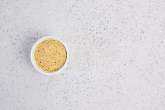 Amaranth seeds in white ceramic bowl isolated on grey backround from above.