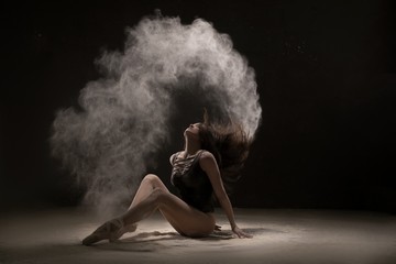 Fototapeta na wymiar Brunette on the floor in white dust cloud