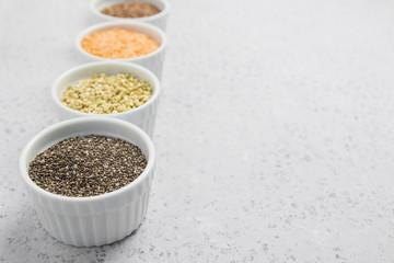 Collection of different groats on grey background. Top view of buckwheat, chia, flax, amaranth, lentils, couscous, wheat