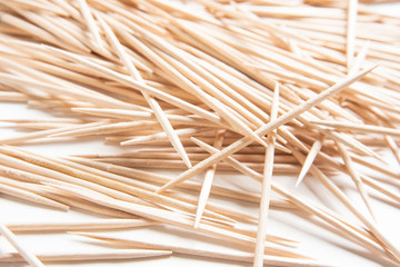 A bunch of unused round toothpicks from light-colored wood arrayed on a white plain background.