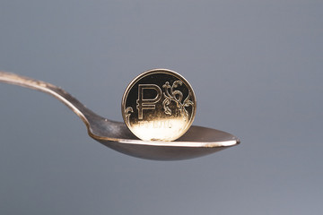 coin in a teaspoon of metal light on the coin, the Russian ruble