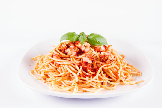 Spaghetti bolognese with melted parmesan cheese decorated with basil on a white background
