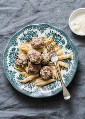 Cream sauce roasted meatballs with penne pasta on a gray background, top view