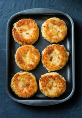 Potato bread crumbs baked cakes on a baking tray on a dark background, top view