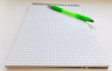 Checkered Notepad and a pencil on a white background. Things for study and work. Top view of a pad and pencil