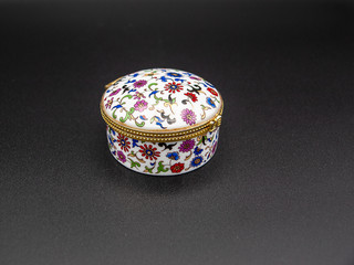 Beautifully ornamented closed porcelain jewelry box with a floral motive isolated on a black...