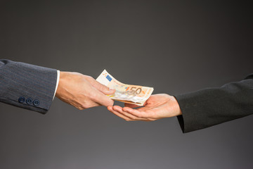 Deal! Businessman paying money  (fifty euros) to businesswoman. Woman and man hand on a gray...
