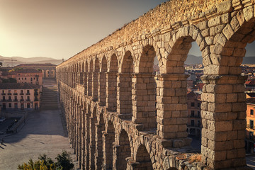 Perspective view of the roman aqueduct of the city of Segovia, next to some houses of the urban center, Segovia, Spain - obrazy, fototapety, plakaty