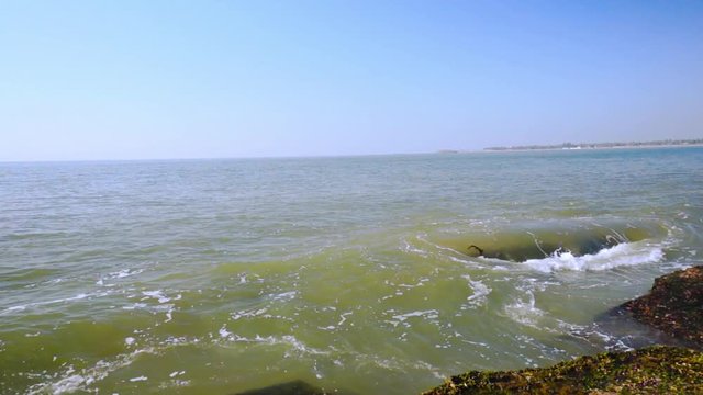 Waves dashing against the moss covered rocks on a beach in Diu, Gujarat, India