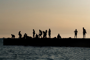 Fototapeta na wymiar Silhouette photo of people resting on the pier after sunset. 