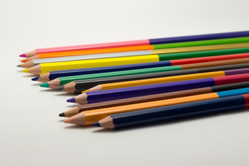 Double sided mulitcolored pencils in a row on white background.