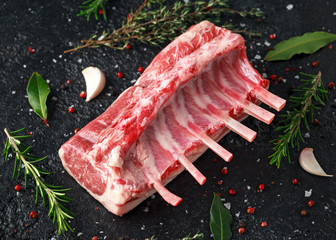 raw fresh rack of lamb with green herbs.