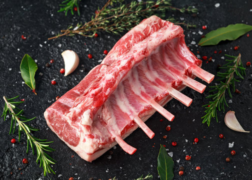 raw fresh rack of lamb with green herbs.