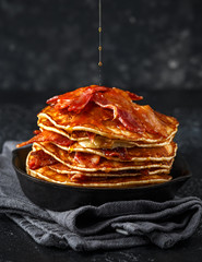 Pancakes with crispy bacon and maple syrup in cast iron skillet, frying pan. Morning Breakfast