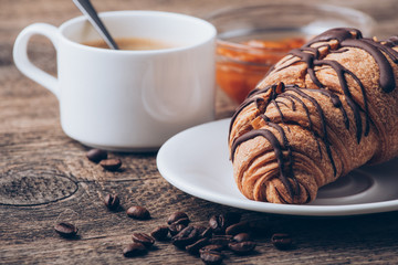 Breakfast with coffee, milk and croissants on wooden table
