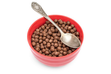 Red bowl with chocolate corn balls and spoon on white.