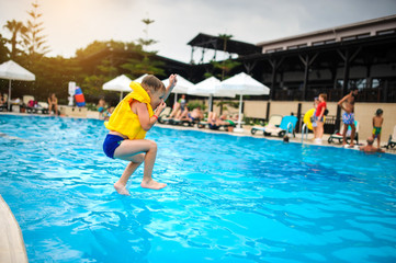 a 6-year blond boy in a life vest jumping in the swimming pool of a hotel in Turkey