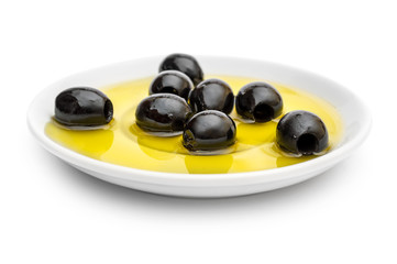 Saucer with black olives in oil on white.