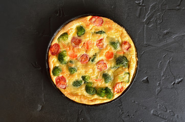 Omelet with broccoli and tomatoes in frying pan