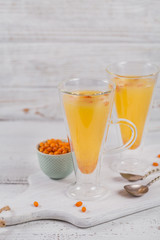 Two high glasses with colorful hot sea buckthorn tea with fresh sea buckthorn berries