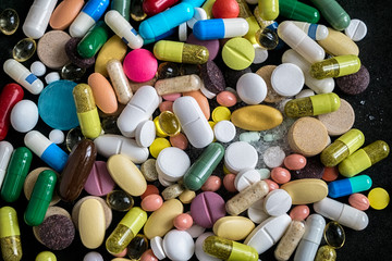 Pharmaceutical tablets, capsules, therapy drugs and pills on black background, top view